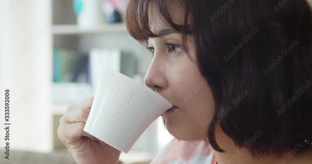Young pretty woman drinking hot beverage while looking on TV Young pretty woman drinking hot beverage while looking on TV