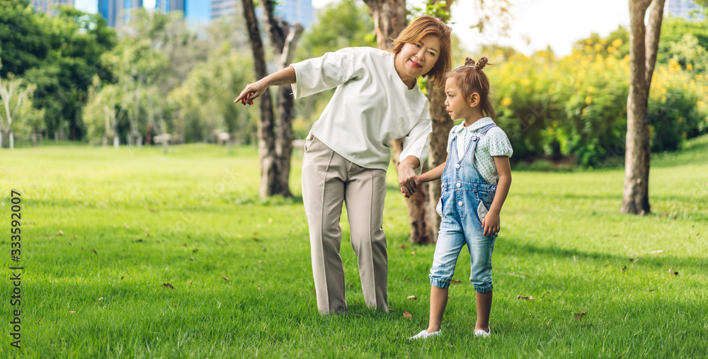 Fototapeta premium Portrait of enjoy happy love asian family grandmother and little cute girl child having fun relax play together moments good time in summer park.asia family and togetherness