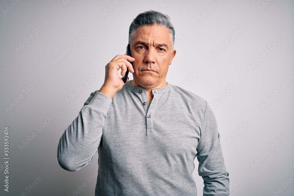 Middle age handsome grey-haired man having conversation talking on the smartphone with a confident expression on smart face thinking serious Middle age handsome grey-haired man having conversation talking on the smartphone with a confident expression on smart face thinking serious