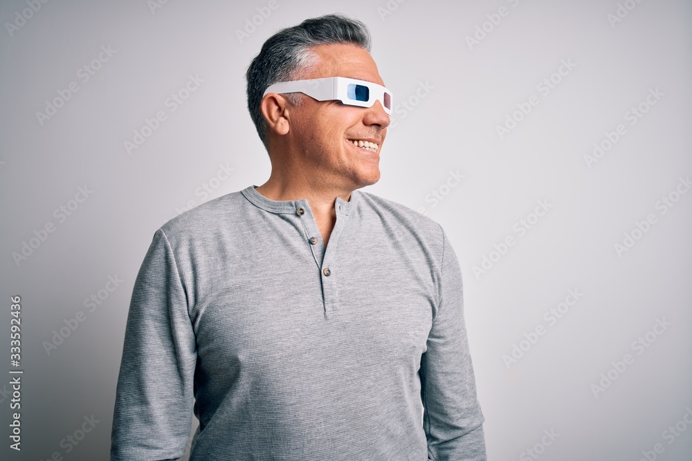 Middle age handsome grey-haired man using 3d glasses over isolated white background looking away to side with smile on face, natural expression. Laughing confident. Middle age handsome grey-haired man using 3d glasses over isolated white background looking away to side with smile on face, natural expression. Laughing confident.