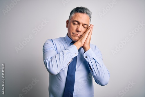 Middle age handsome grey-haired business man wearing elegant shirt and tie sleeping tired dreaming and posing with hands together while smiling with closed eyes.