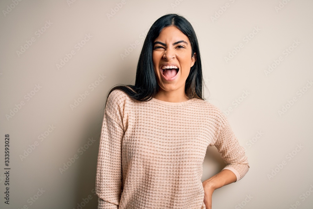 Young beautiful hispanic woman wearing elegant pink sweater over isolated background winking looking at the camera with sexy expression, cheerful and happy face.