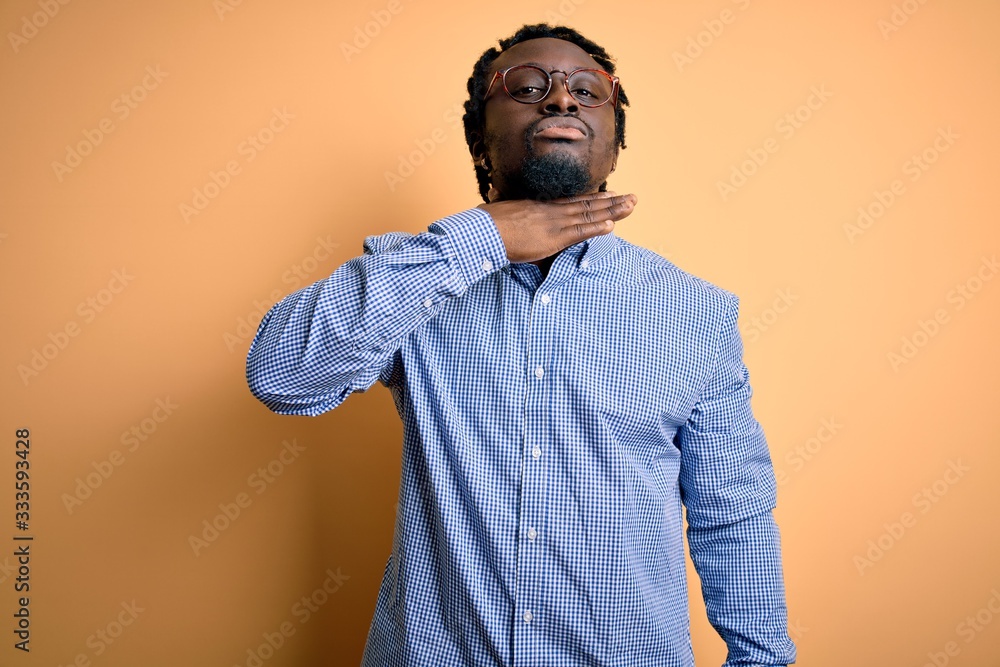 Young handsome african american man wearing shirt and glasses over yellow background cutting throat with hand as knife, threaten aggression with furious violence Young handsome african american man wearing shirt and glasses over yellow background cutting throat with hand as knife, threaten aggression with furious violence