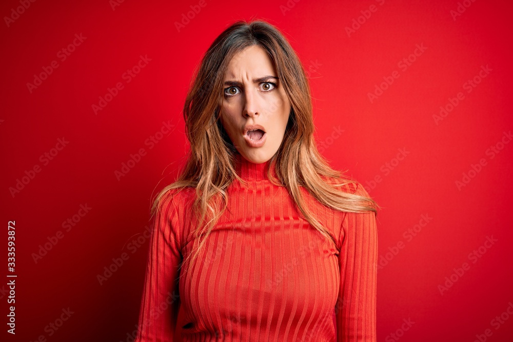 Young beautiful brunette woman wearing casual turtleneck sweater over red background In shock face, looking skeptical and sarcastic, surprised with open mouth Young beautiful brunette woman wearing casual turtleneck sweater over red background In shock face, looking skeptical and sarcastic, surprised with open mouth