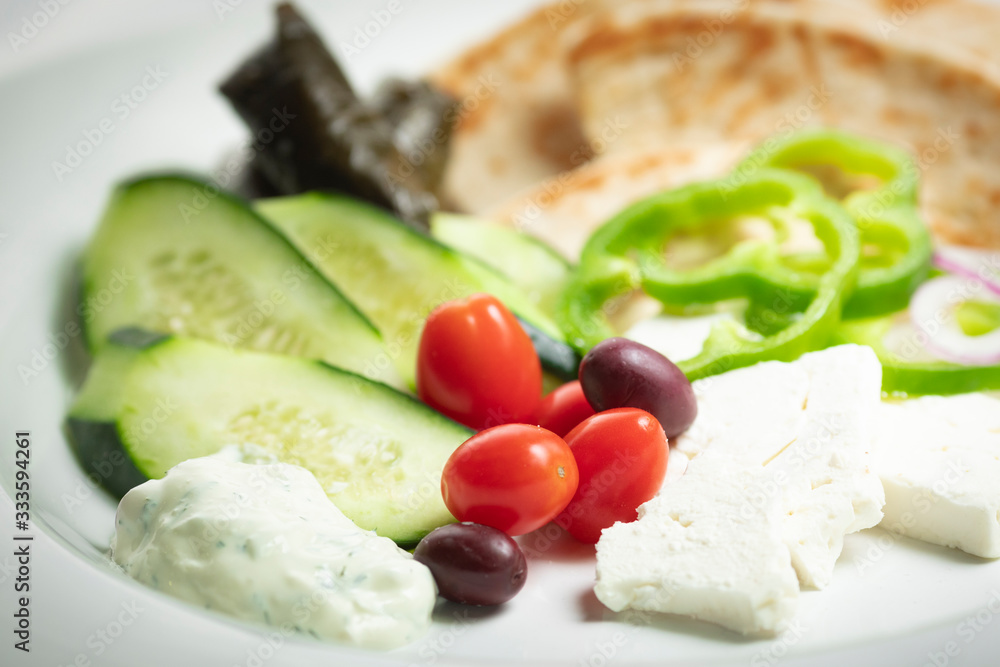 Shallow focus view of simple Greek meze food platter; with vegetables, pita, feta, and grape leaves Shallow focus view of simple Greek meze food platter; with vegetables, pita, feta, and grape leaves