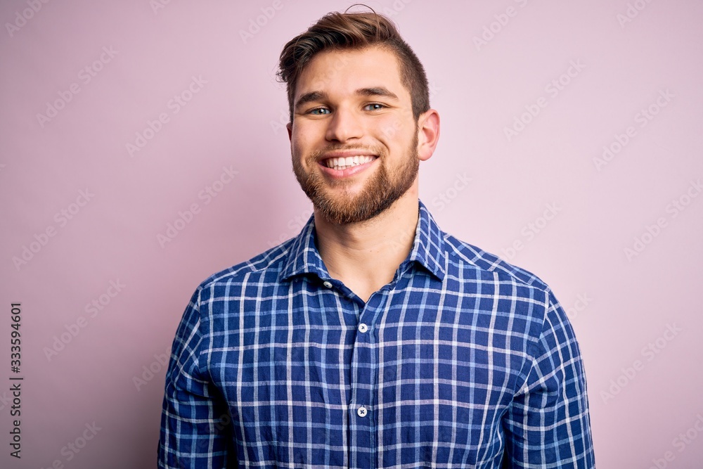 Young handsome blond man with beard and blue eyes wearing casual shirt standing with a happy and cool smile on face. Lucky person. Young handsome blond man with beard and blue eyes wearing casual shirt standing with a happy and cool smile on face. Lucky person.
