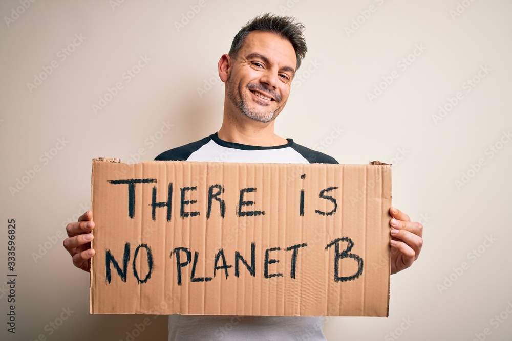Young handsome man asking for environment holding banner with planet message with a happy face standing and smiling with a confident smile showing teeth Young handsome man asking for environment holding banner with planet message with a happy face standing and smiling with a confident smile showing teeth