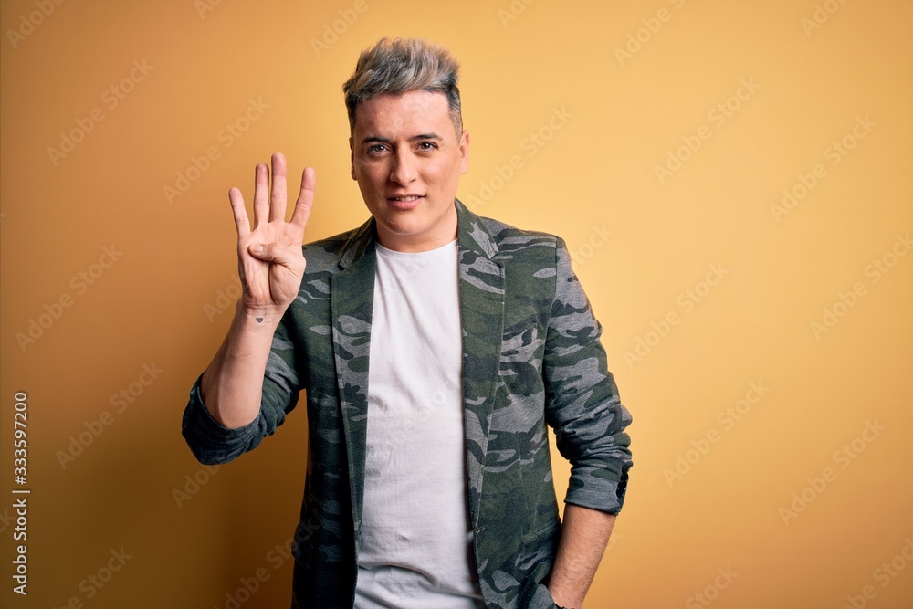 Young handsome modern man wearing business jacket standing over yellow isolated background showing and pointing up with fingers number four while smiling confident and happy. Young handsome modern man wearing business jacket standing over yellow isolated background showing and pointing up with fingers number four while smiling confident and happy.