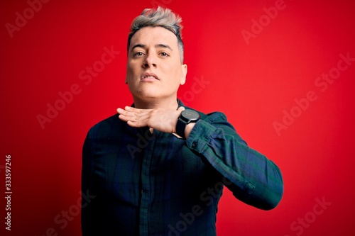 Young handsome modern man wearing elegant green shirt over red isolated background cutting throat with hand as knife, threaten aggression with furious violence