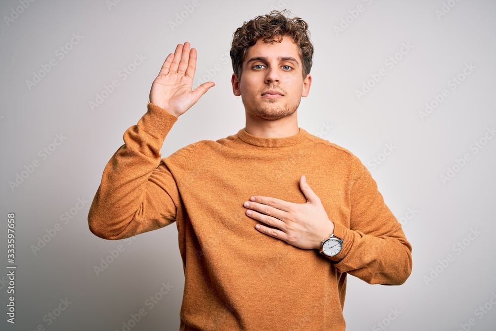 Young blond handsome man with curly hair wearing casual sweater over white background Swearing with hand on chest and open palm, making a loyalty promise oath Young blond handsome man with curly hair wearing casual sweater over white background Swearing with hand on chest and open palm, making a loyalty promise oath