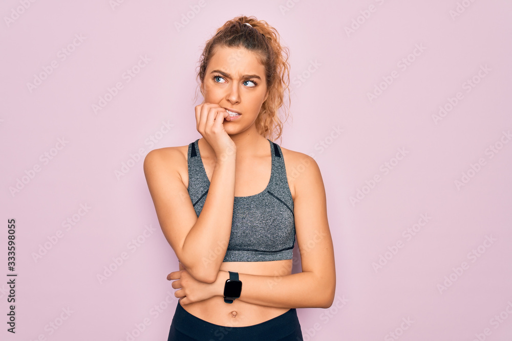 Young beautiful blonde sportswoman with blue eyes doing exercise wearing sportswear looking stressed and nervous with hands on mouth biting nails. Anxiety problem. Young beautiful blonde sportswoman with blue eyes doing exercise wearing sportswear looking stressed and nervous with hands on mouth biting nails. Anxiety problem.