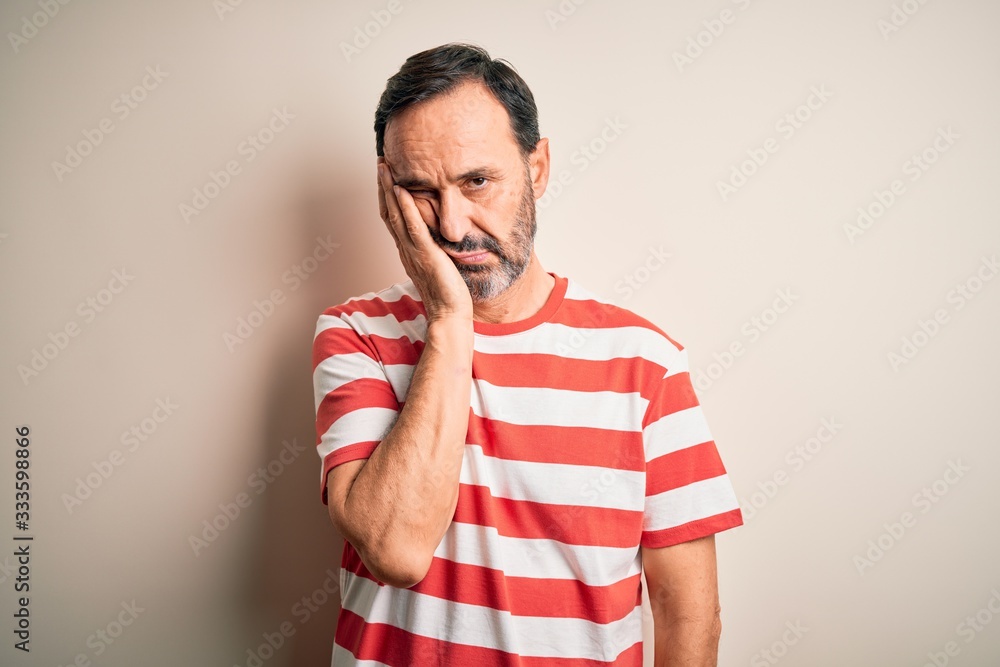 Middle age hoary man wearing casual striped t-shirt standing over isolated white background thinking looking tired and bored with depression problems with crossed arms. Middle age hoary man wearing casual striped t-shirt standing over isolated white background thinking looking tired and bored with depression problems with crossed arms.