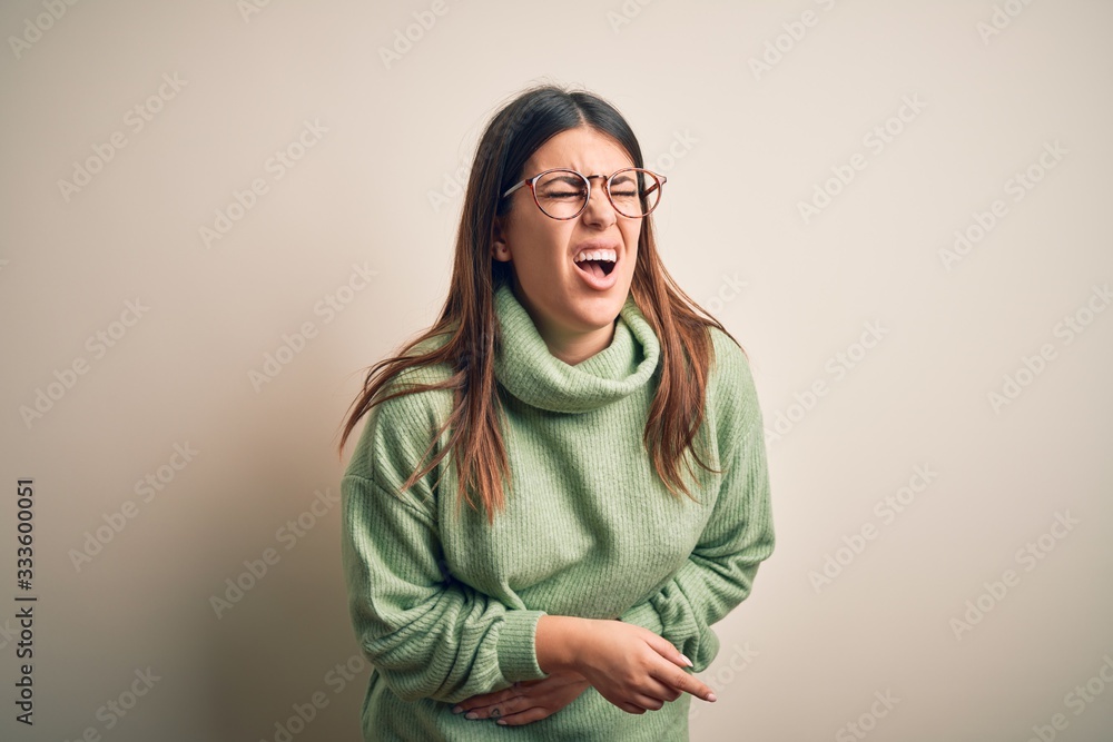 Young beautiful woman wearing casual sweater standing over isolated white background with hand on stomach because nausea, painful disease feeling unwell. Ache concept. Young beautiful woman wearing casual sweater standing over isolated white background with hand on stomach because nausea, painful disease feeling unwell. Ache concept.