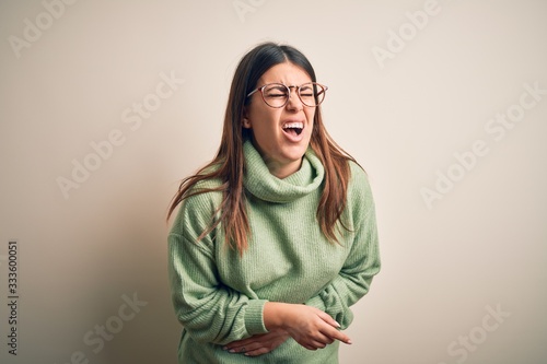 Young beautiful woman wearing casual sweater standing over isolated white background with hand on stomach because nausea, painful disease feeling unwell. Ache concept.