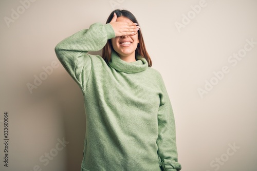 Young beautiful woman wearing casual sweater standing over isolated white background smiling and laughing with hand on face covering eyes for surprise. Blind concept. © Krakenimages.com