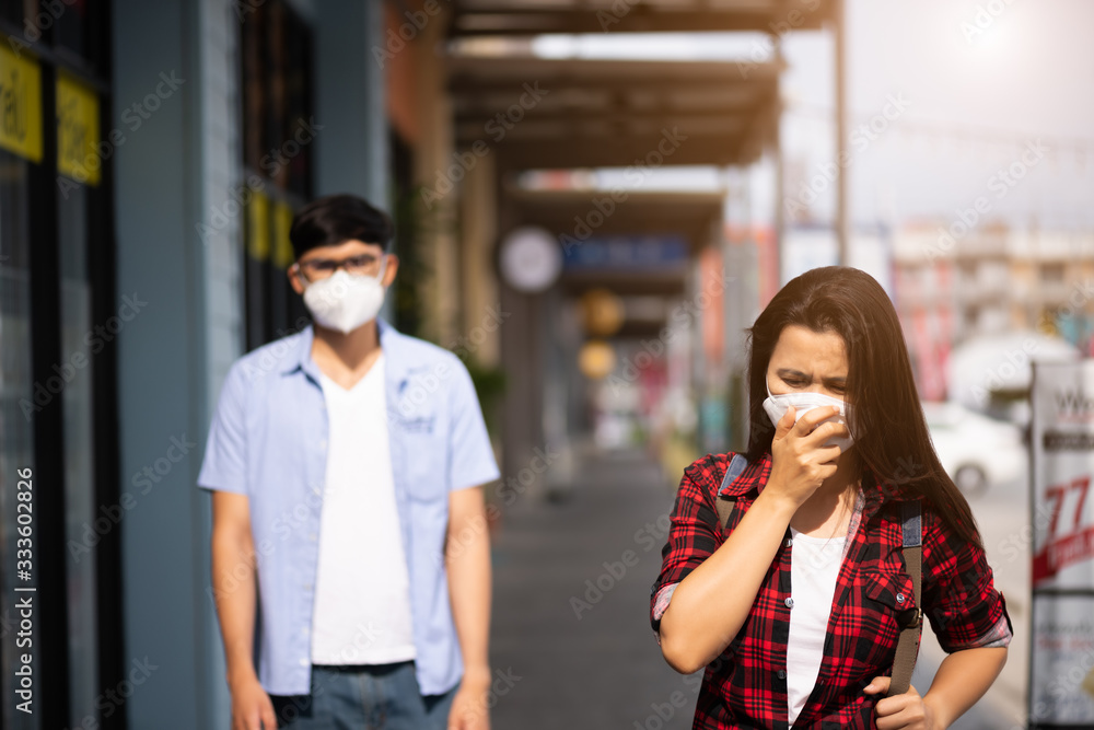 Close up of woman and man wearing Protective face mask and cough, get ready for Coronavirus and pm 2.5 fighting during waking outdoor shopping mall in background. Close up of woman and man wearing Protective face mask and cough, get ready for Coronavirus and pm 2.5 fighting during waking outdoor shopping mall in background.
