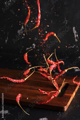 Falling dried red hot chili with sichuan pepper seasoning mala powder on wood board isolated background