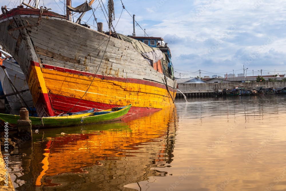 Traditional wooden sailing ships park at a local old harbor in Jakarta with blue sky before sun set. Traditional wooden sailing ships park at a local old harbor in Jakarta with blue sky before sun set.