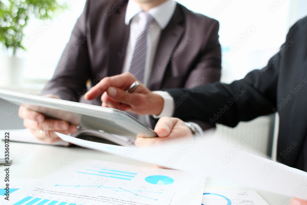 Two businessman are looking and studying statistics on tablet display closeup. Male hand opponent holds pen and points out problem collaboration business coach cooperation partnership palm concept Two businessman are looking and studying statistics on tablet display closeup. Male hand opponent holds pen and points out problem collaboration business coach cooperation partnership palm concept
