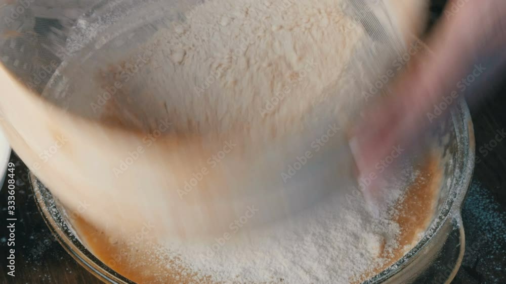 Female hands sift flour through a special sieve in the home kitchen. Future home baking dough. Female hands sift flour through a special sieve in the home kitchen. Future home baking dough.