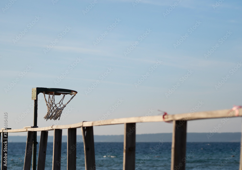 a basketball goal set at wooden pier with sea view background.