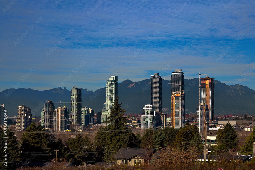 Fototapeta premium Construction of new high-rise buildings in residential district in the city of Burnaby, construction site, new high-rises and construction cranes against the backdrop of a mountain ridge