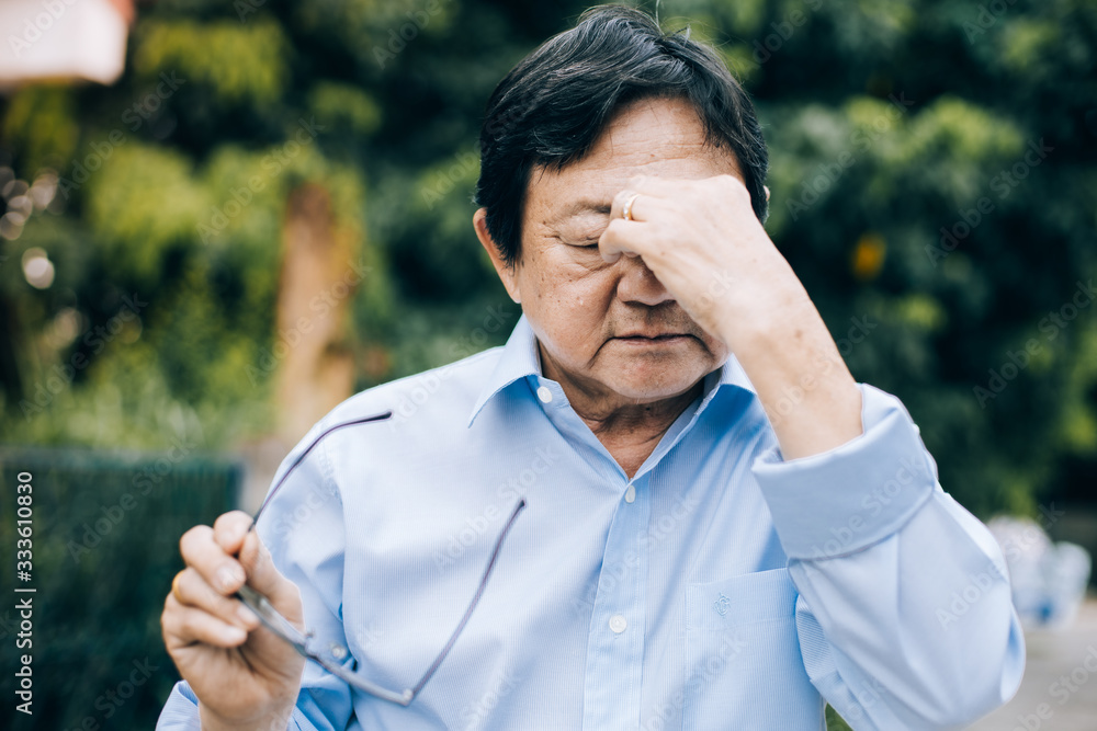 Portrait of an elderly man with headache.senior man covering his face with his hands.vintage tone Portrait of an elderly man with headache.senior man covering his face with his hands.vintage tone