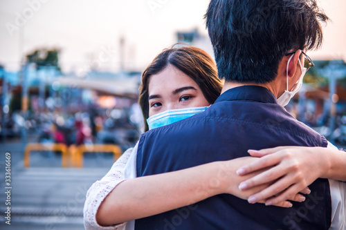 Young millennials couple hugging and wearing a protective face mask, virus spread prevention and people concept © CravenA