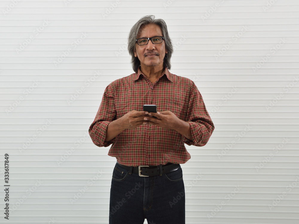 Happy senior businessman in red casual shirt, blue jeans and eyeglasses  using smart mobile phone standing over white wall background, Business  communication concept Stock Photo | Adobe Stock