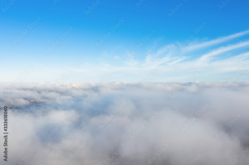 Aerial view of cloudscape layers of soft fluffy clouds over the city on a summer sunny day.