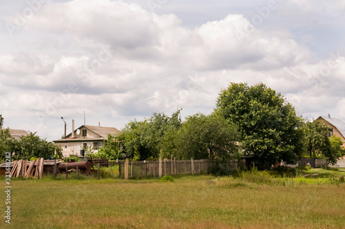 Green meadow with trees and houses far away. Small town