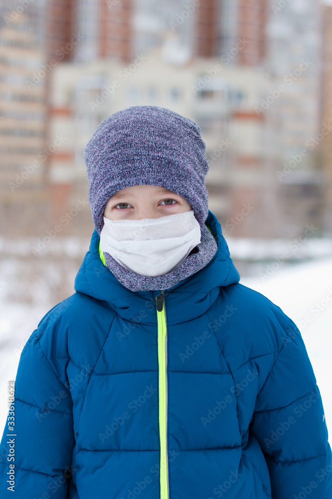 The danger of coronavirus. A boy on a walk walks in a medical mask on his face The danger of coronavirus. A boy on a walk walks in a medical mask on his face