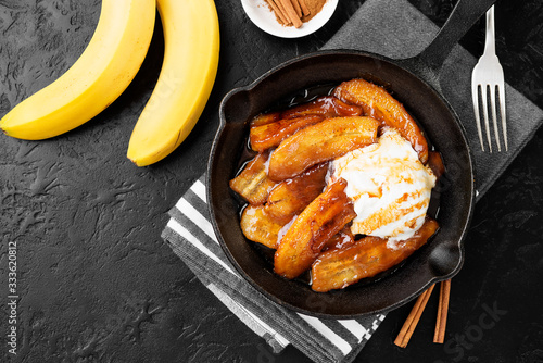 Fotografia Homemade fried bananas foster with cinnamon and ice cream in cast iron pan