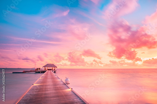 Fototapeta Naklejka Na Ścianę i Meble -  Sunset on Maldives island, luxury water villas resort and wooden pier. Beautiful sky and clouds and beach background for summer vacation holiday and travel concept. Paradise sunset landscape