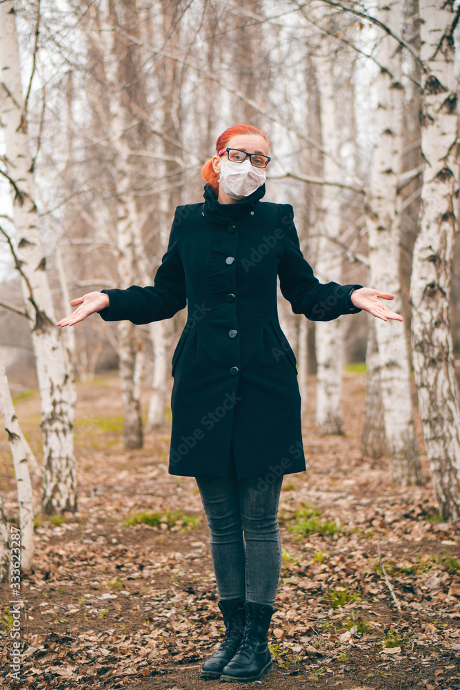 Masked girl with glasses shrugs outdoor. Protection against virus concept.