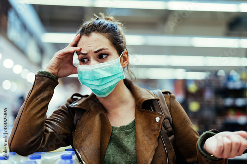 Young woman wearing face mask and feeling worried while being at the store during virus pandemic.