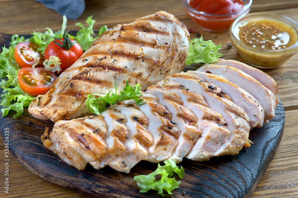 grilled chicken breast with fresh vegetables on a chopping Board