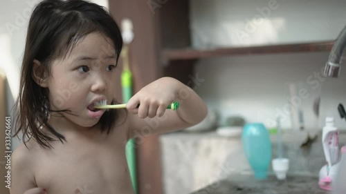 Asian little girl brushing her teeth at morning. Real life and Handheld shot