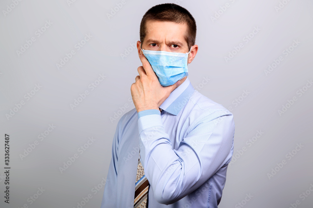 Thoughtful man in medical mask, thinks, holds hand at head Thoughtful man in medical mask, thinks, holds hand at head