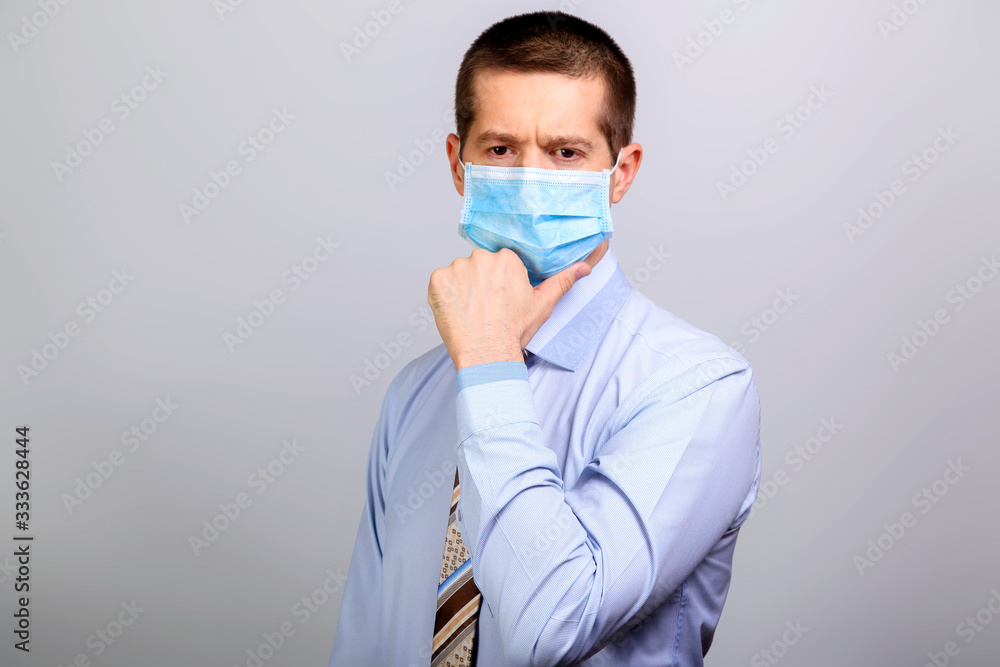 Thoughtful man in medical mask, thinks, holds hand at head Thoughtful man in medical mask, thinks, holds hand at head