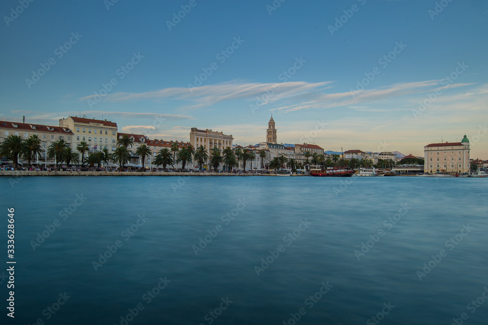 Fototapeta premium Evening panorama of Split in croata, visible famous Diocletian palace and bell tower. Some ships moored in port, blue and calm evening skies.