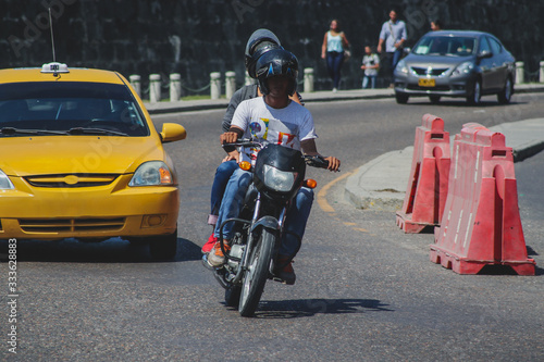 Motorcycle taxi in Cartagena, Colombia. Motorbike driver driving with a customer as pillion between busy traffic photo