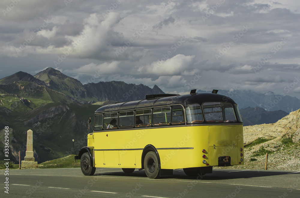 Old vintage bus or coach in yellow and black color driving on the top of Grossglockner high alpine road up in the Austrian alps