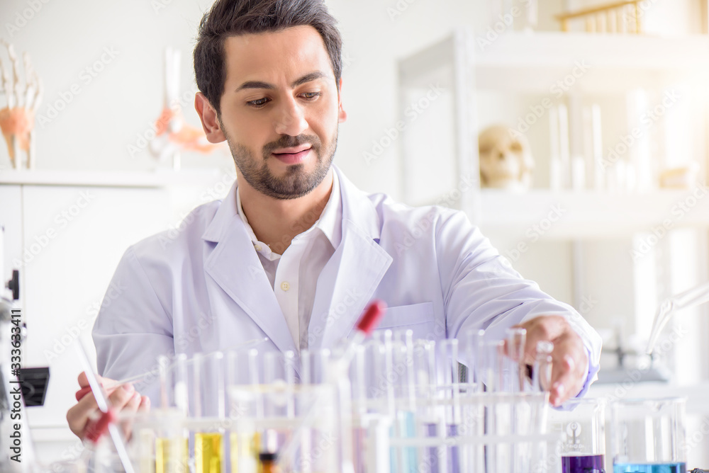 Attractive happiness scientist man lab technician assistant analyzing sample in test tube at laboratory. Medical, pharmaceutical and scientific research and development concept.