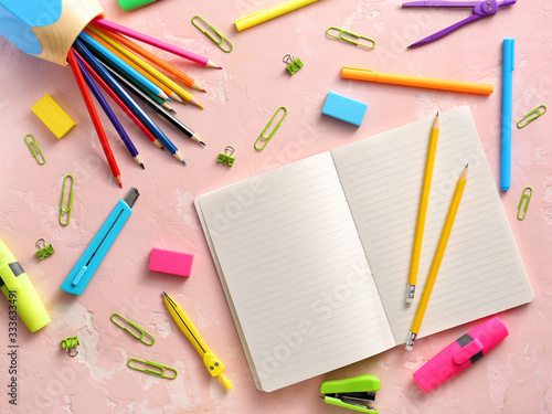 Notebook with school supplies on color background