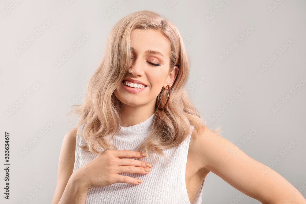 Young blonde with beautiful hair on light background Young blonde with beautiful hair on light background