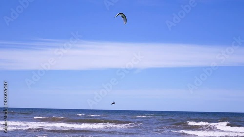 Kite surfer is jumping high in the air, and performing a trick,