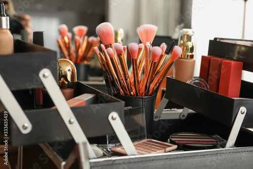 Box with set of brushes and decorative cosmetics on table of makeup artist