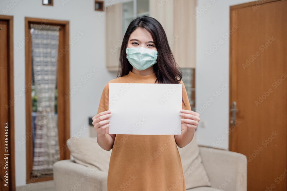 Portrait of a cheerful and healthy young woman asian wearing medical mask holding a empty sheet of paper. Portrait of a cheerful and healthy young woman asian wearing medical mask holding a empty sheet of paper.