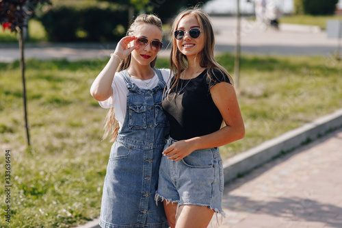 two young pretty girls on a walk in the park. a sunny summer day, joy and friendships. © pressahotkey